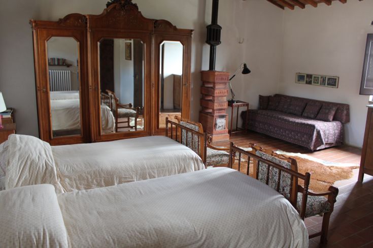 Simple room with single beds, wooden wardrobe, and a sofa, perfect for a peaceful stay.