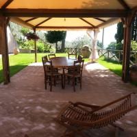 Scène du porche d'une ferme, aménagé pour des repas en plein air, entouré de verdure.