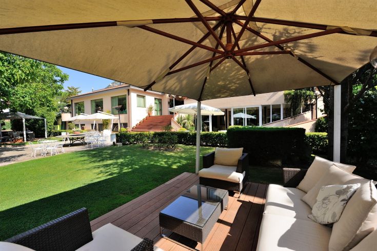 Un espace extérieur confortable avec des canapés, des parasols et une végétation abondante.