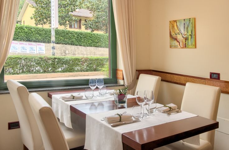 Image d'un restaurant avec des tables bien ordonnées et une vue sur un jardin bien entretenu.