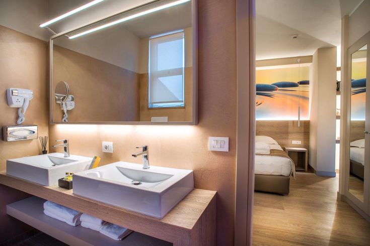 Salle de bains contemporaine avec deux lavabos, miroir éclairé et design moderne.