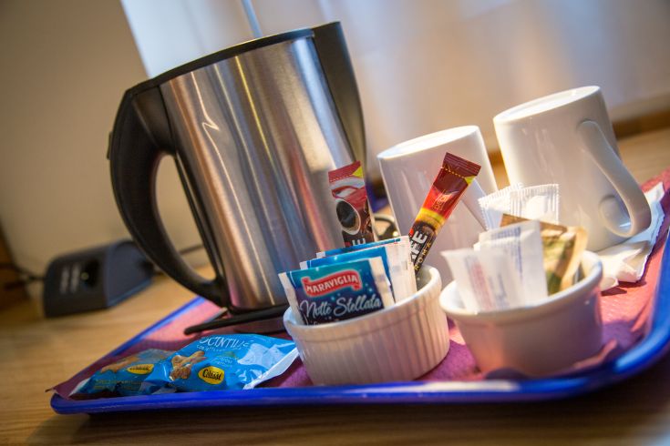 A tray with tea, coffee, and pastries in a relaxing hotel environment.