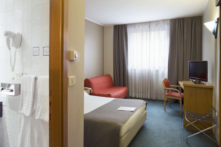 Simple hotel room with comfortable beds and a small relaxation area.