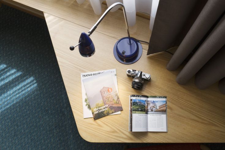 A hotel table featuring a lamp, a camera, and informative brochures about the Umbria region.