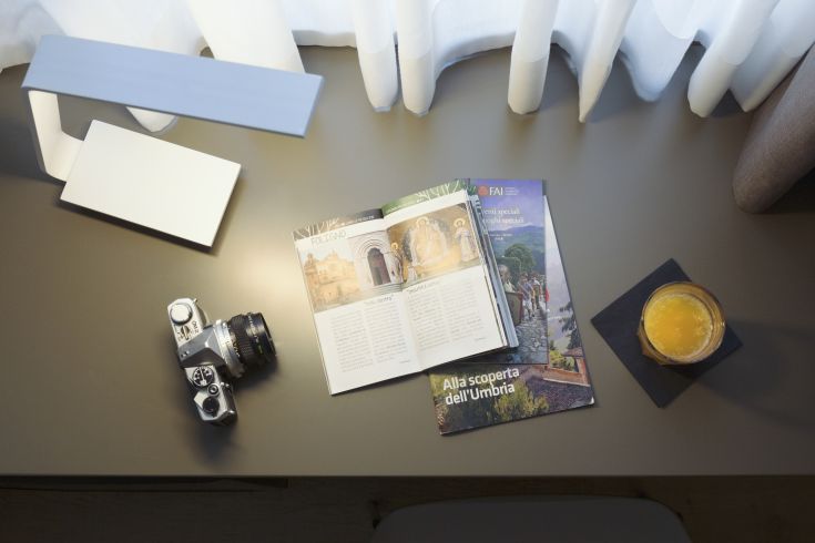 A moment of tranquility in a hotel room, with a book and a drink, in a simple and well-kept environment.
