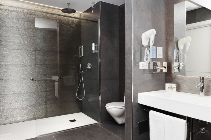 Simple bathroom with a spacious shower and practical furnishings, exuding functionality.