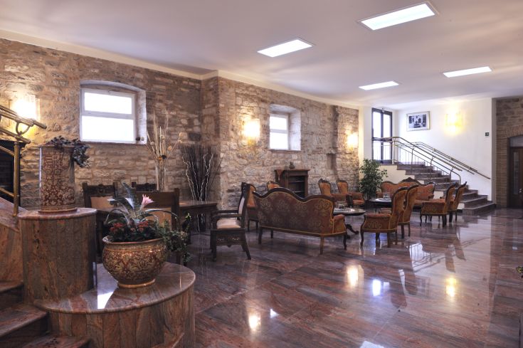 Ein klassisches Wohnzimmer mit einfachen Möbeln und Steindetails. Das natürliche Licht schafft eine gemütliche Atmosphäre.