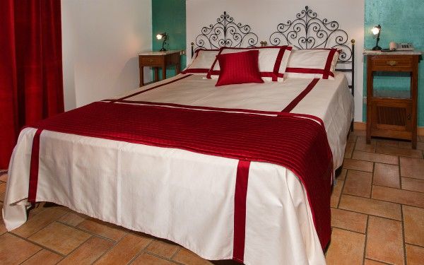 Einfaches Schlafzimmer mit Doppelbett und roten Dekorationen.