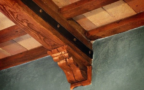 Detail eines Holzträgers mit einfachen Oberflächen, Wände in zartem Grün gestrichen.