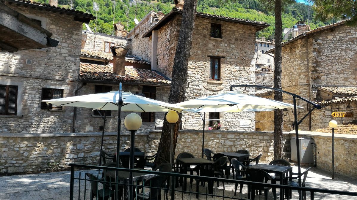 A charming corner of Gubbio featuring stone buildings and a pleasant outdoor space.
