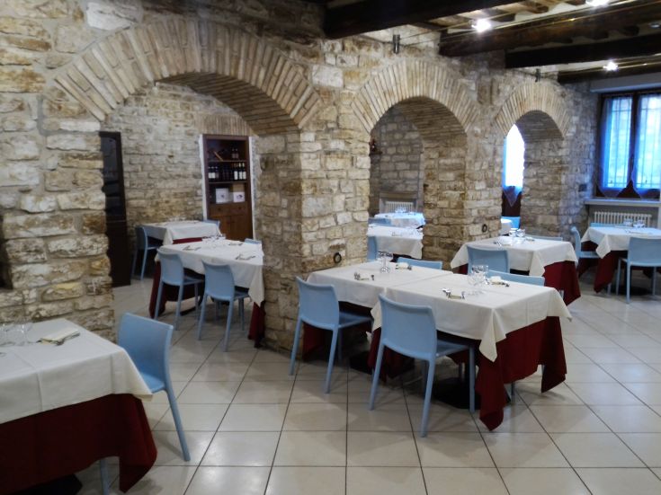Ristorante semplicemente arredato con archi in pietra e tavoli ordinati.