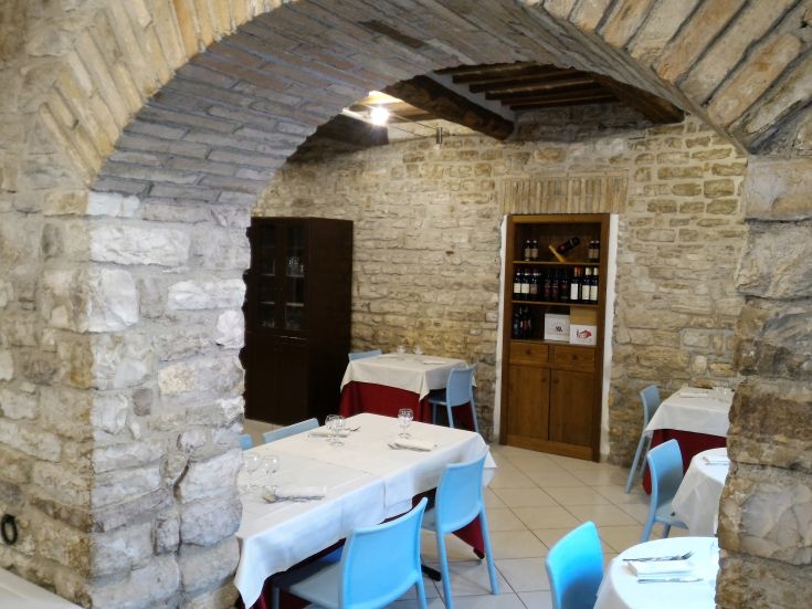 Un ristorante accogliente con pareti in pietra e tavoli arredati in modo curato.