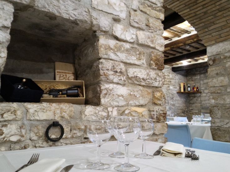 Una sala ristorante caratterizzata da pareti in pietra e tavoli curati, che trasmette un'atmosfera storica.