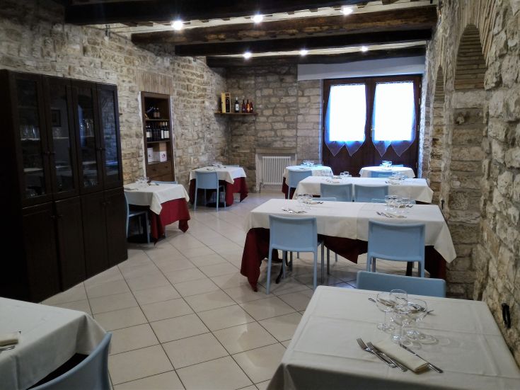 Ristorante con pareti in pietra e tavoli semplici, adatto per assaporare piatti tipici dell'Umbria.