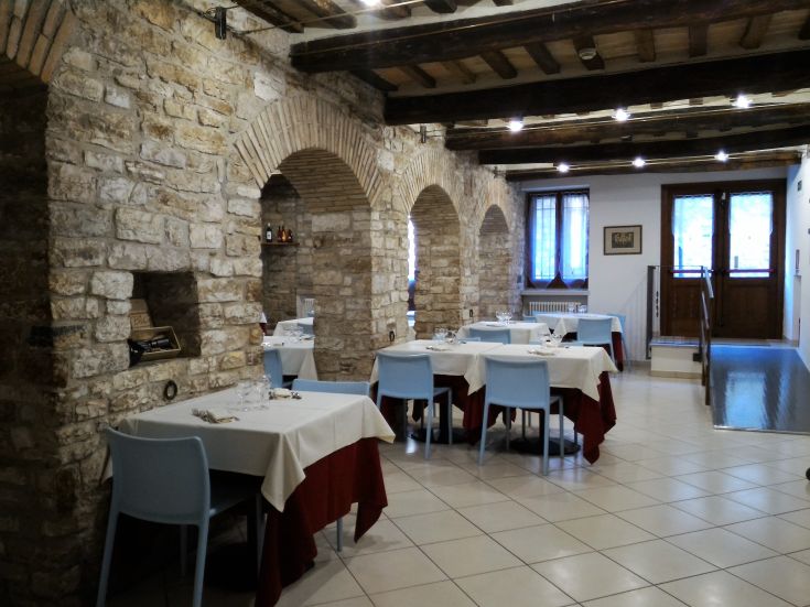 Interno di un ristorante con pareti in pietra e tavoli semplicemente apparecchiati.