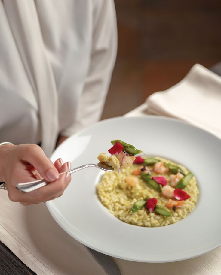 Ein Risotto mit Garnelen und frischem Gemüse, serviert in einer weißen Schüssel.