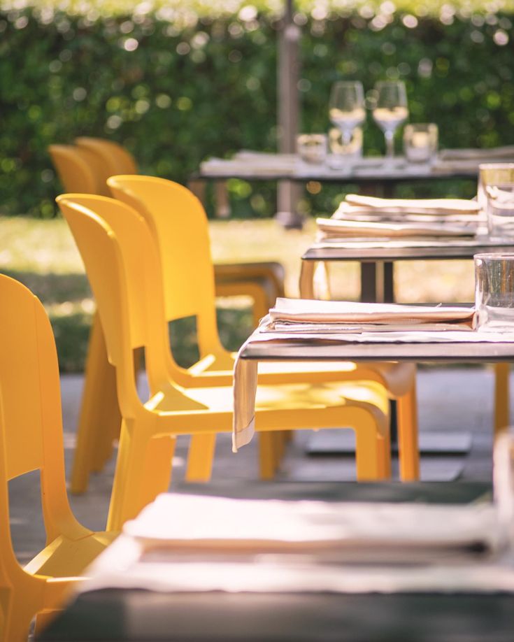 Ruhige Außengastronomie mit gelben Stühlen und gedeckten Tischen, ideal für ein Mittagessen im Freien.