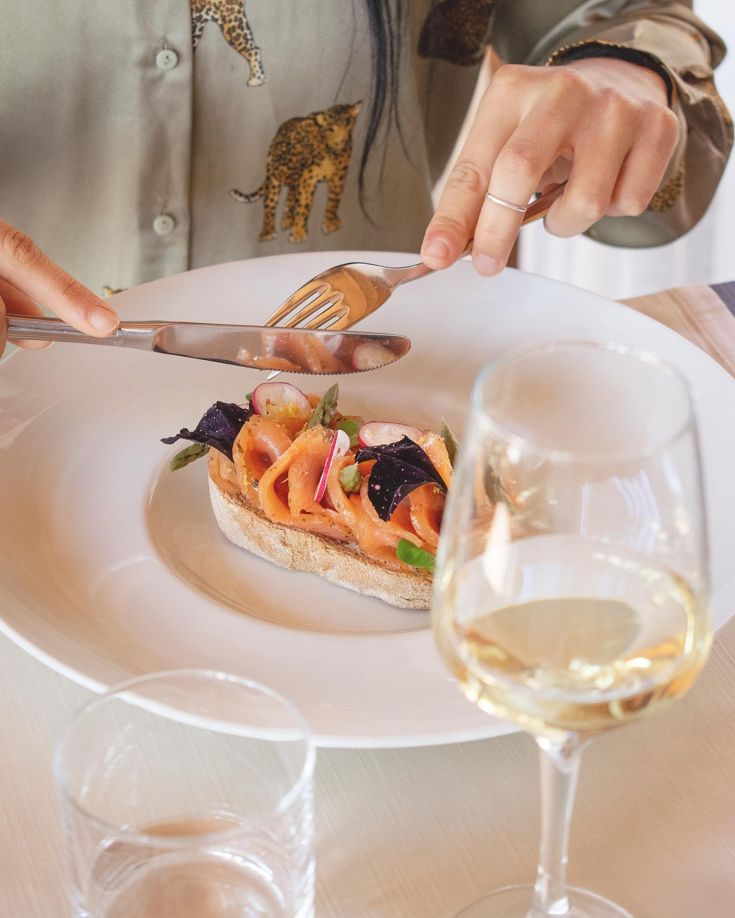 Ein Gourmetgericht mit geräuchertem Lachs, serviert mit einem frischen Salat und einem Glas Weißwein.
