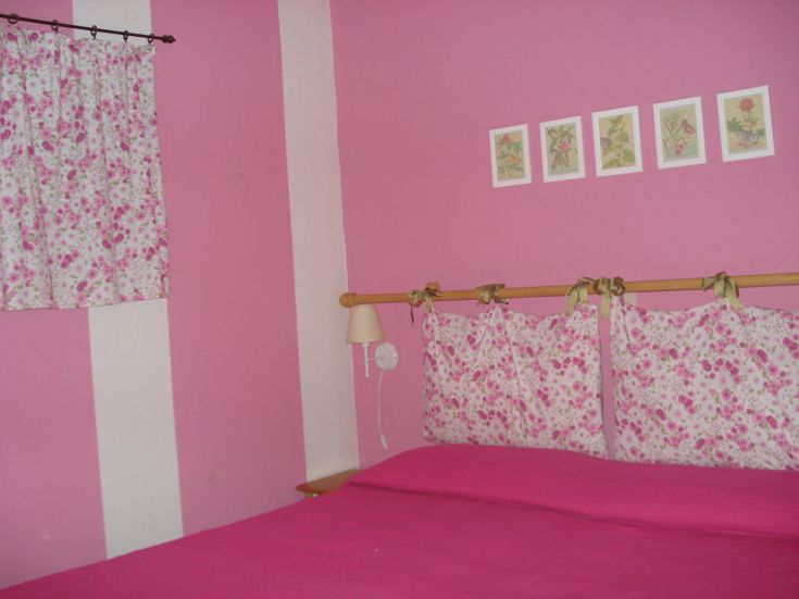 A pink room decorated with floral curtains and cushions. A cozy and tranquil space.
