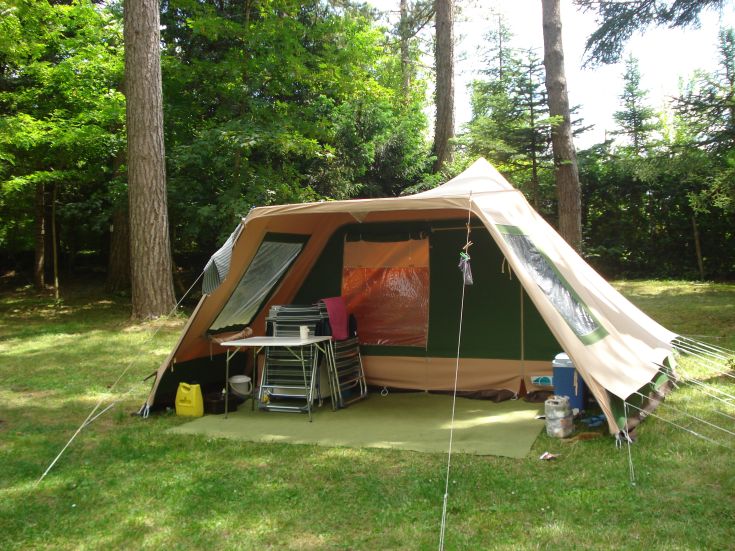 A tent located in the woods, surrounded by trees and lush green vegetation.