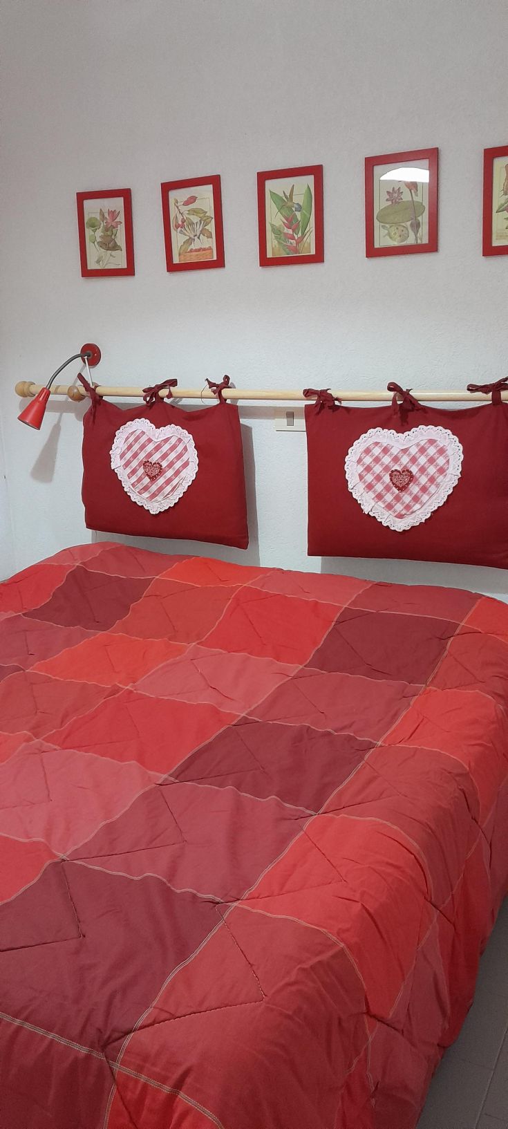 A cozy room with red sheets, warm-colored blankets, and heart-shaped pillows.
