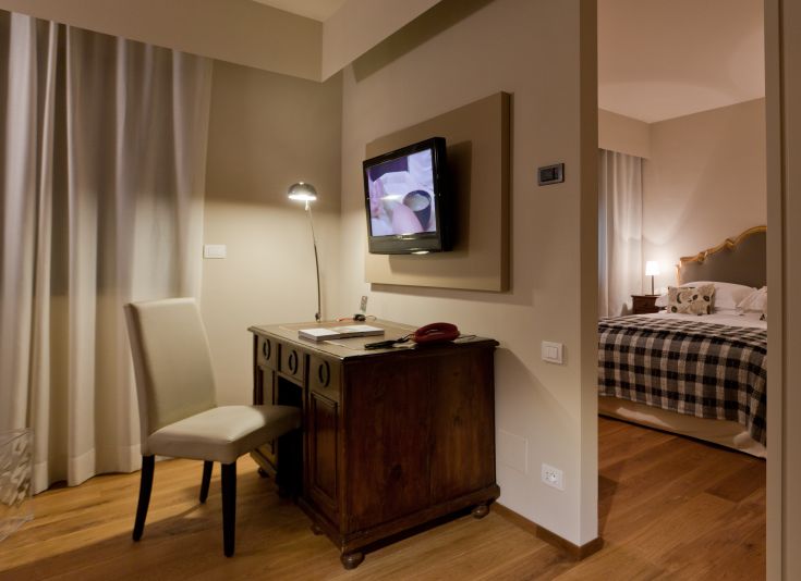 Une chambre simple avec un bureau en bois et une télévision, située dans un bâtiment sobre.