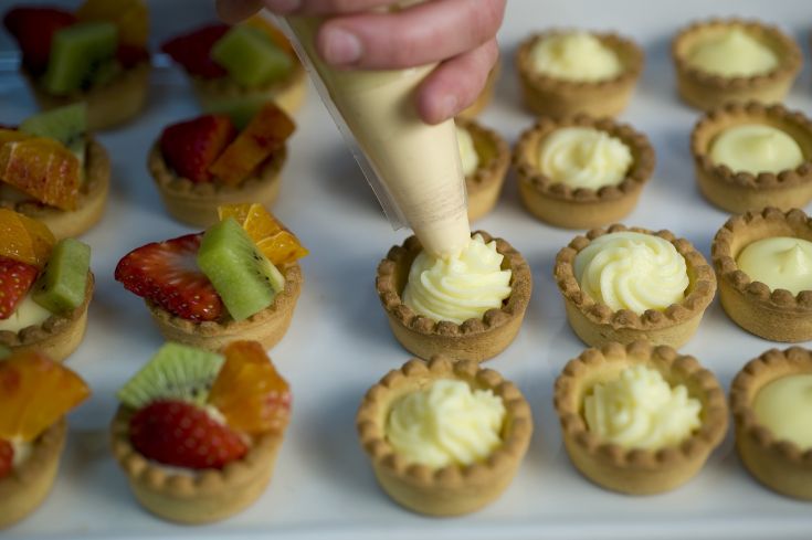 Tartelettes sucrées garnies de crème et décorées de fruits frais, idéales pour un dessert léger et rafraîchissant.