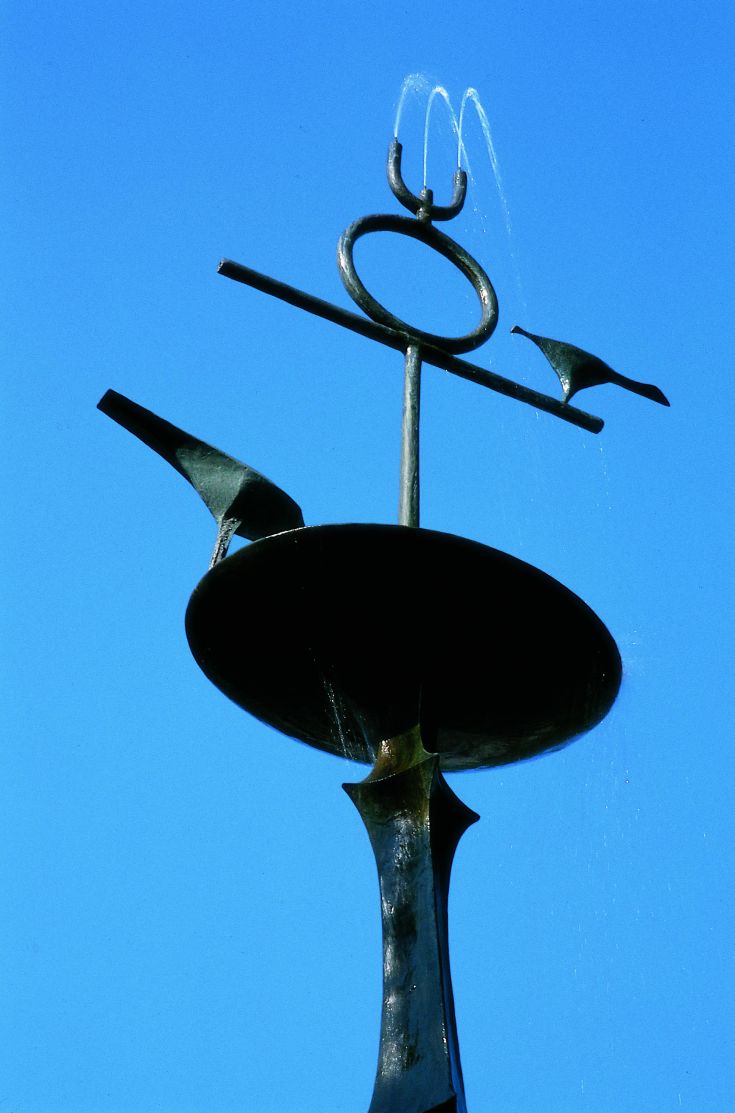 Fontaine décorative dans un cadre extérieur, entourée de végétation verte.