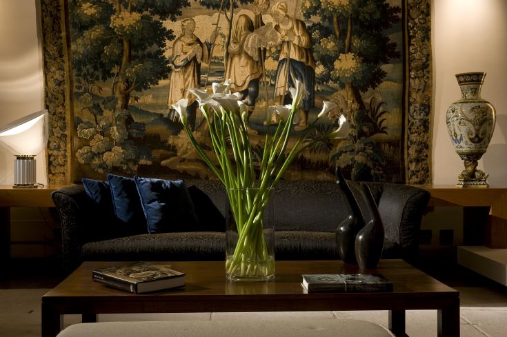 Un salon confortable avec un canapé et des fleurs dans un vase, décoré de tapisseries et d'objets décoratifs.