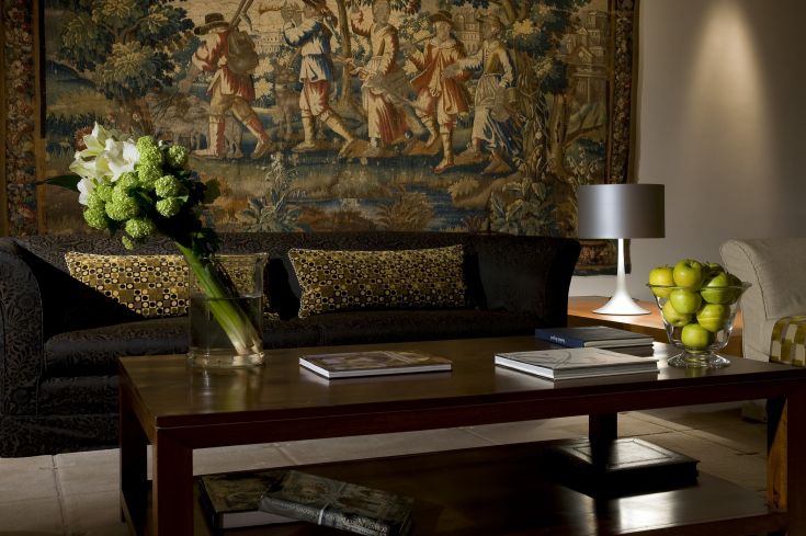 Un salon simple avec un canapé sombre et une table en bois ; une peinture décorative complète le décor.