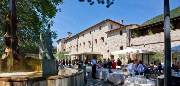 Un ancien monastère rénové qui sert d'hôtel, entouré d'un paysage naturel typique de l'Ombrie.