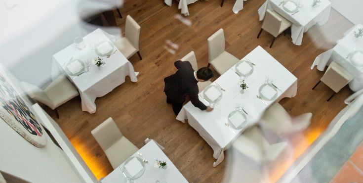 Un restaurant avec des tables bien rangées et un serveur qui sert les clients.