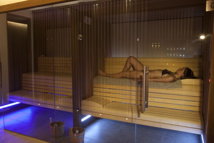 Ambiance relaxante dans le sauna avec des lumières chaleureuses et des détails en bois clair, idéale pour un moment de bien-être.