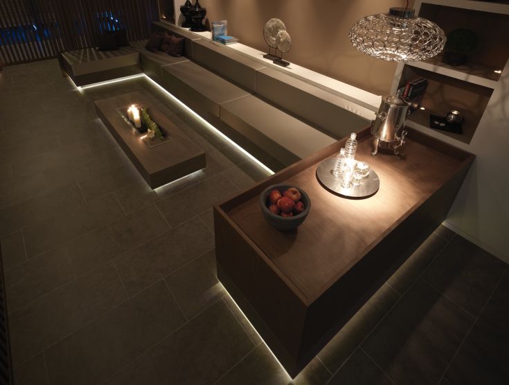 Intérieur accueillant avec un éclairage chaud, table en bois avec des fruits et des lampes modernes.