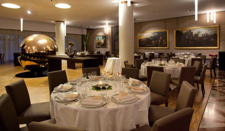 Restaurant avec des tables dressées et des décorations murales. Endroit idéal pour les dîners et les réceptions.