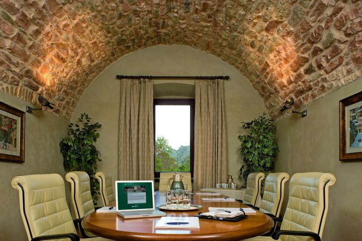 Salle de réunion avec un plafond voûté et des meubles contemporains, donnant sur un jardin.