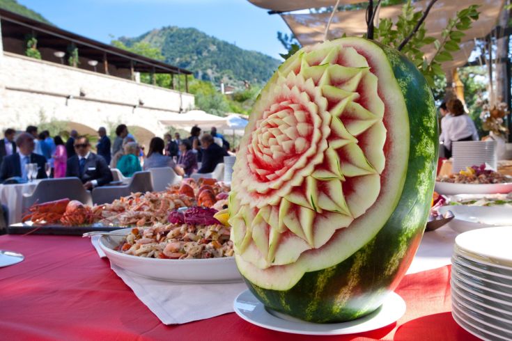 Une pastèque décorée accompagne un banquet élégant en arrière-plan.