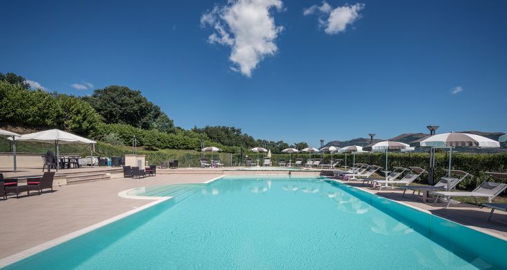 Ein Außenpool, umgeben von Grünflächen, ideal zum Entspannen und Spaß haben im Freien.