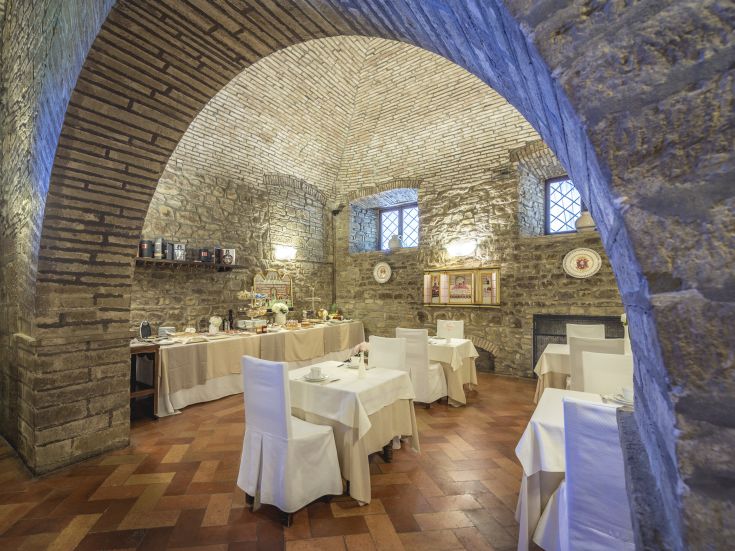 Innerhalb eines Restaurants mit Steinwänden und gewölbter Decke, Tische für die Gäste eingedeckt.