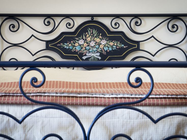 Ein Bett mit einem Kopfteil, das mit einem Blumenstrauß verziert ist, geeignet für eine gemütliche Umgebung.