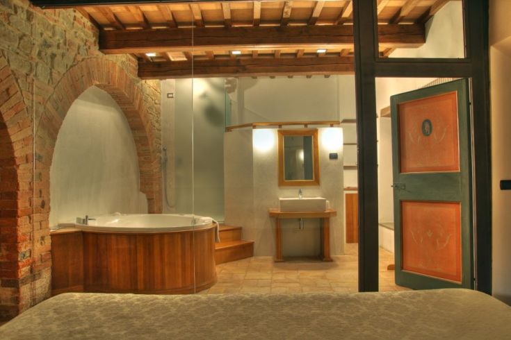 Gut eingerichtetes Badezimmer mit Badewanne und Dusche, rustikale Details in einem renovierten Gebäude.