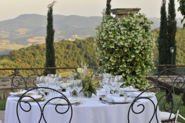 Ein Tisch im Freien mit Blumenarrangements und Blick auf die umliegenden Hügel.