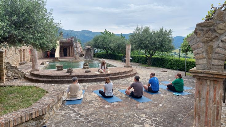 Eine Yoga-Praxis im Freien, umgeben von grünem Natur in einer ruhigen Atmosphäre.