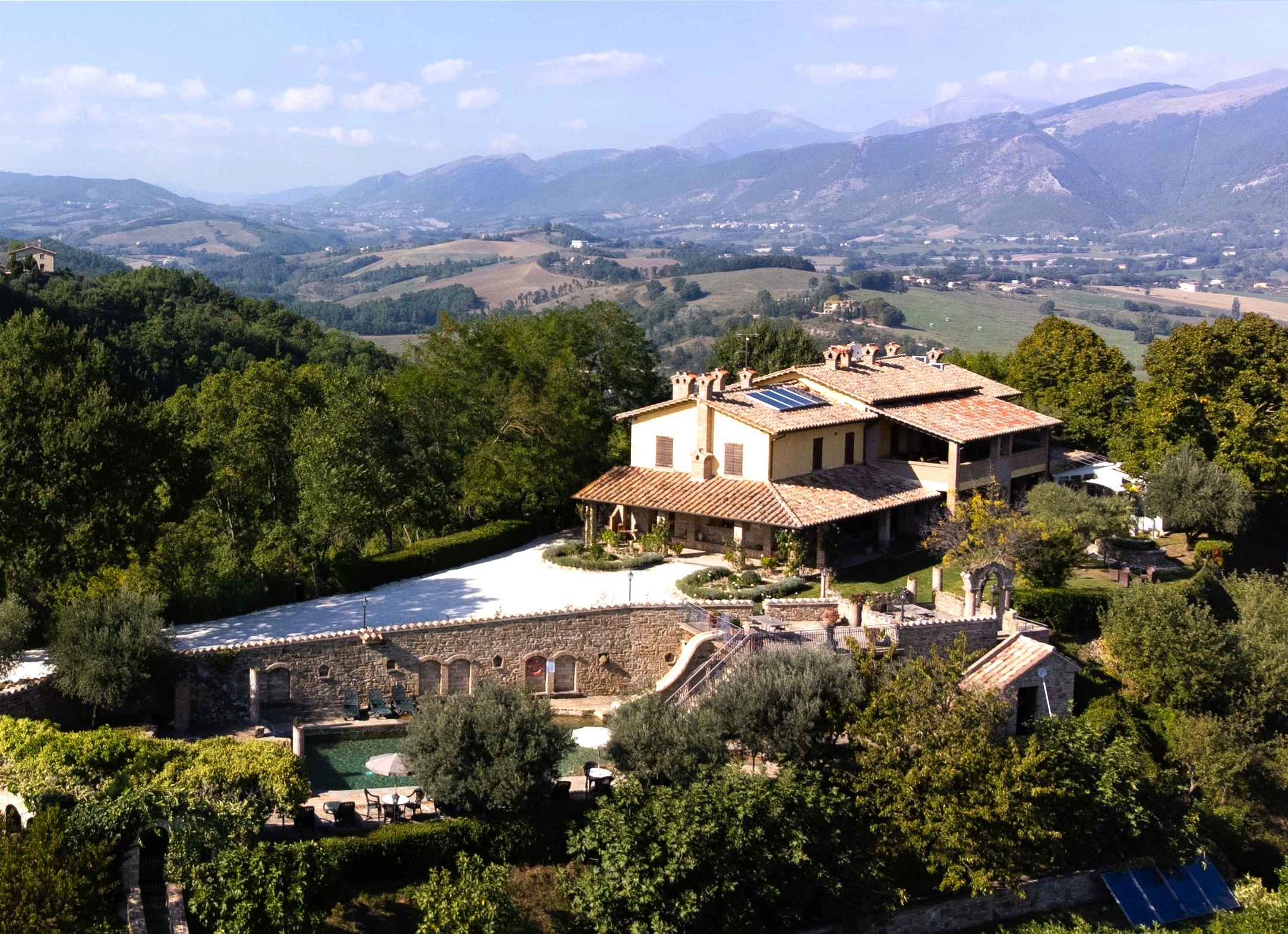 Particolare di un agriturismo circondato dal verde, con panorami su colline e montagne circostanti.