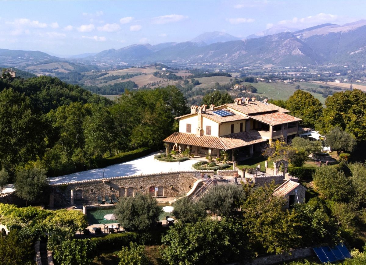 Particolare di un agriturismo circondato dal verde, con panorami su colline e montagne circostanti.