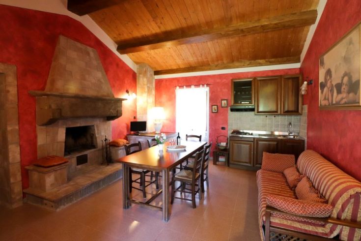 Gemütliche Atmosphäre mit einem Kamin und funktioneller Küche in einem Bauernhof in Umbrien.