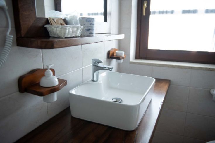 Moderner Waschbecken in einem ordentlichen Bad mit einem Holzspiegel und passenden Accessoires.