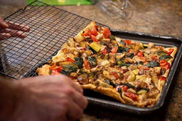 Eine frisch gebackene vegetarische Pizza, belegt mit einer Vielzahl von frischem Gemüse, serviert auf einem einfachen Teller.