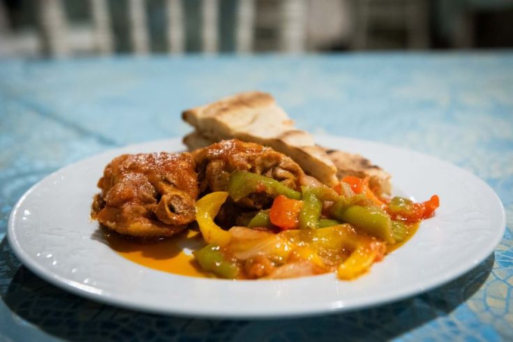 Ein Hühnergericht mit Paprika gekocht, serviert auf einem einfachen weißen Teller.