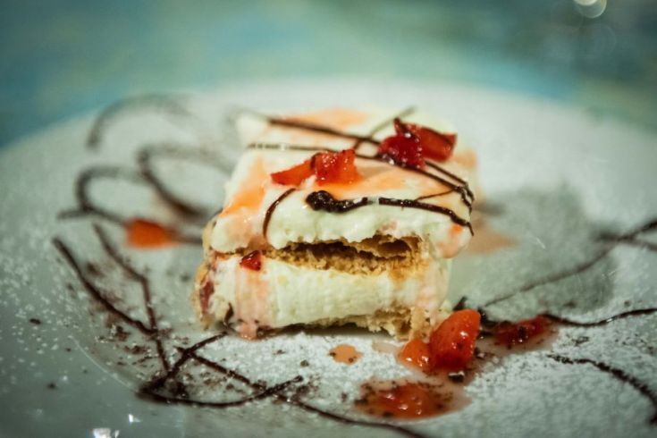 Eine mit frischen Früchten dekorierte Torte, serviert mit Schokoladensauce.